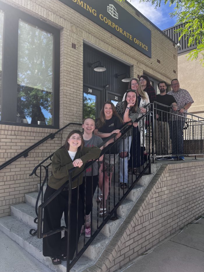 A group of smiling people standing on the steps of a brick building.